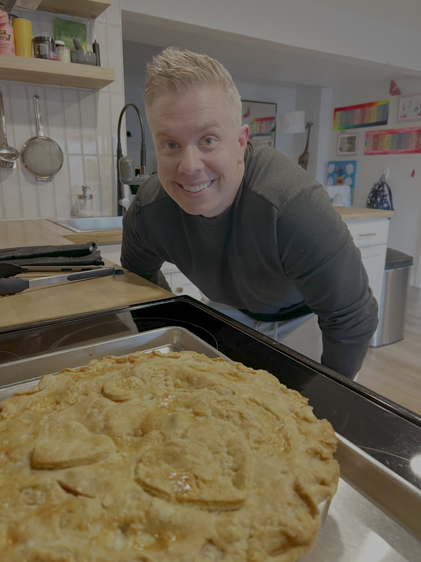 Anthony, founder of Level 99, grinning behind a fresh-baked pie in his kitchen